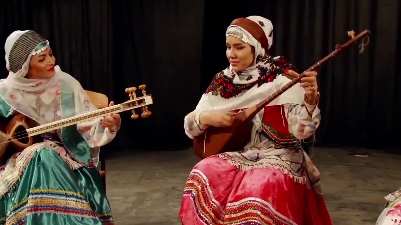 Kurdinnen in traditioneller Kleidung spielen Saiteninstrumente im Iran.